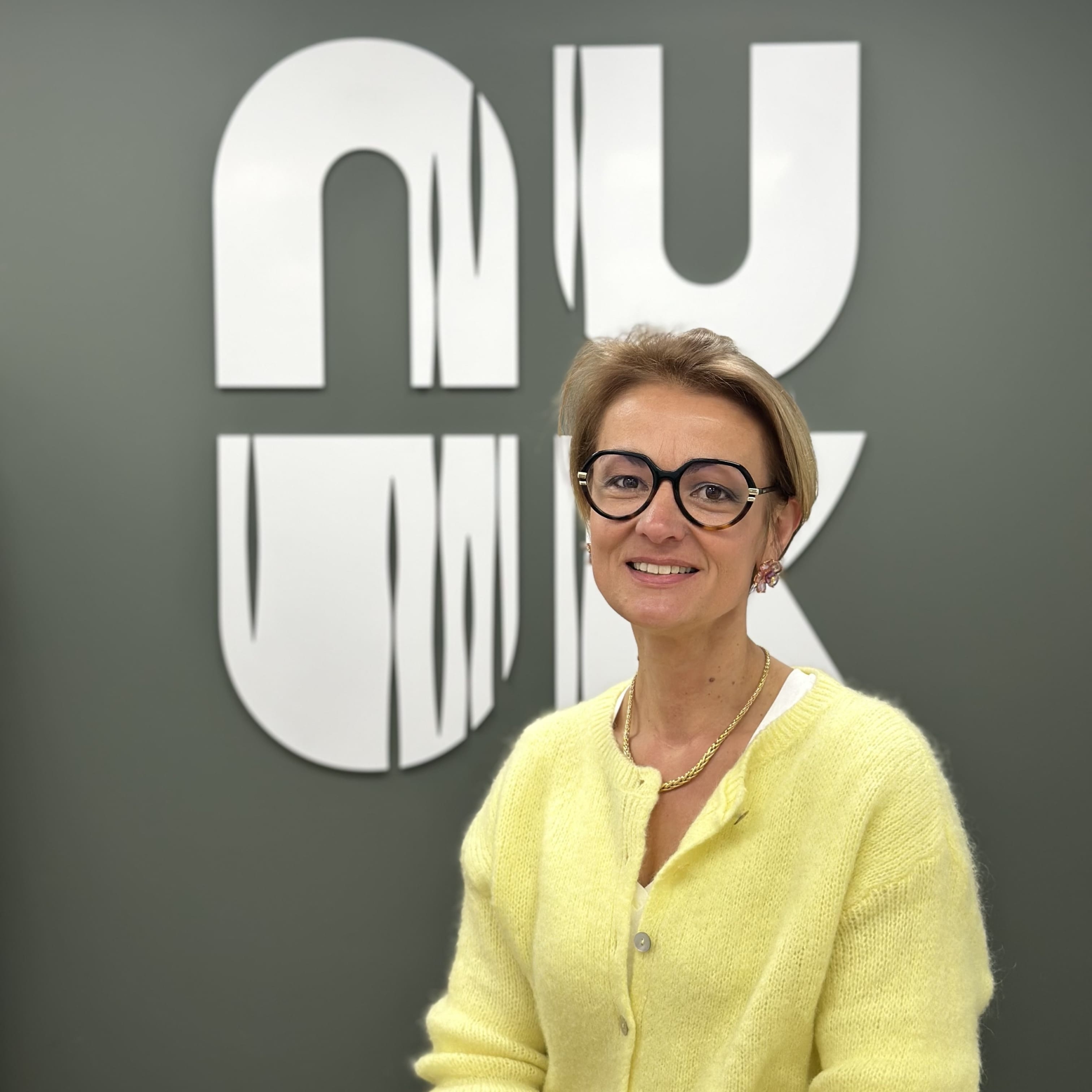 Femme debout qui pose devant le logo Nuuk